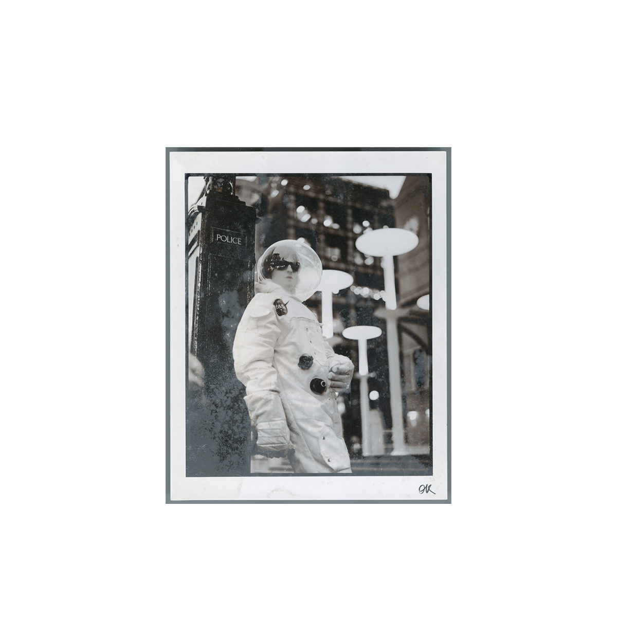 Black and white print of a person in an astronaut suit standing in front of a vintage police box on a city street.