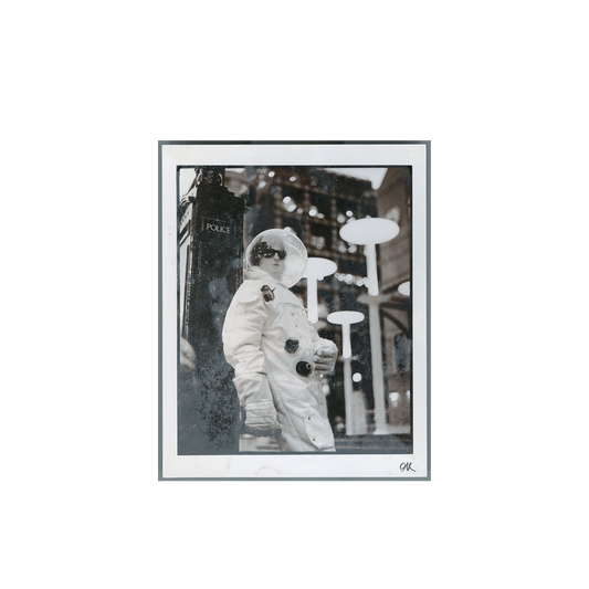 Black and white print of a person in an astronaut suit standing in front of a vintage police box on a city street.
