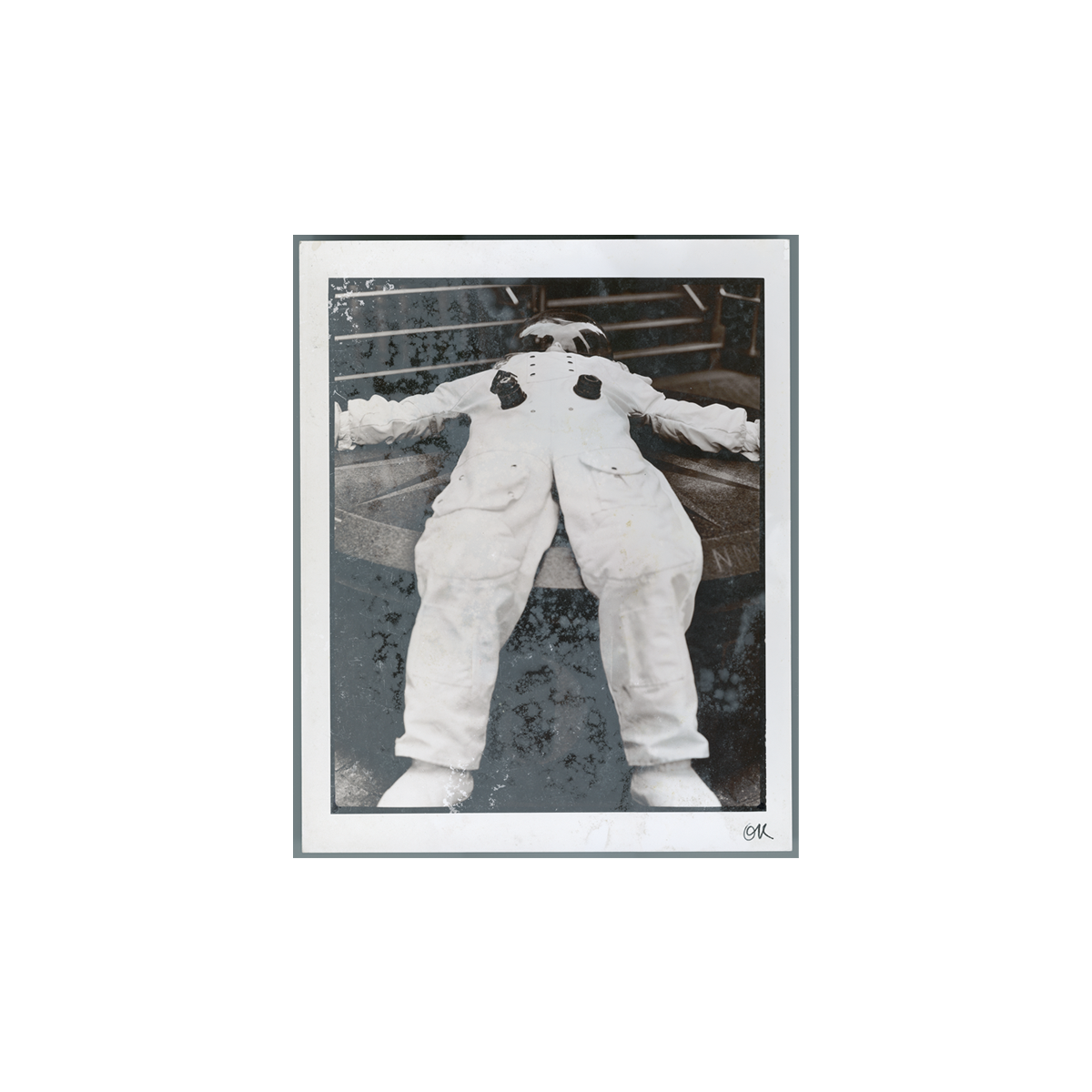 Black and white photo print of a person in a spacesuit lying on their back on metal steps with arms outstretched.
